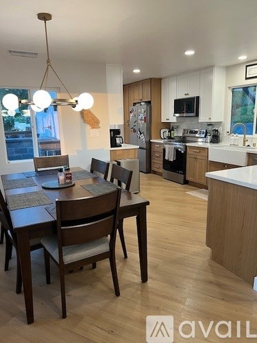 A kitchen with a dining table and chairs in the foreground.