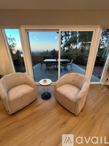 Two chairs are placed in front of a large window with a view of a dining area outside.