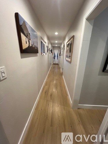 A long hallway with pictures on the wall and wooden floors.