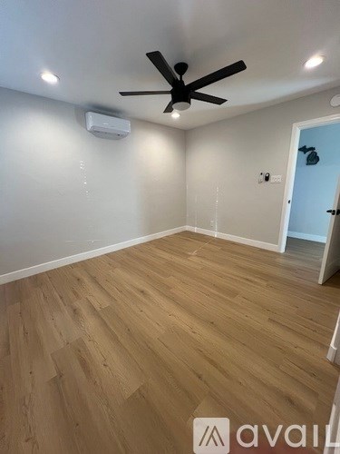 A room with a ceiling fan and wooden flooring.