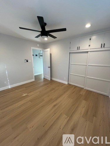 A room with a ceiling fan and wooden flooring.