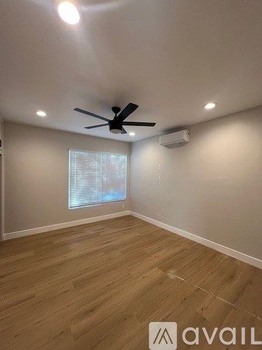 A room with a ceiling fan and wooden flooring.