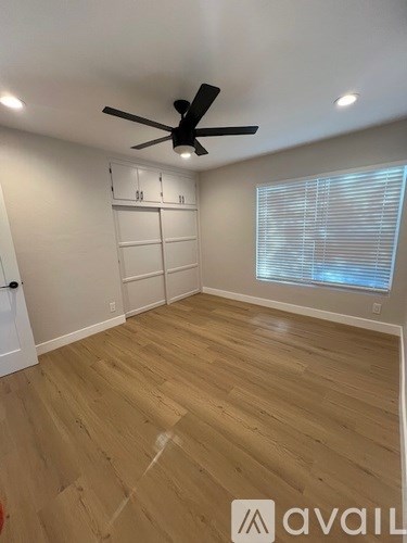 A room with a ceiling fan and wooden flooring.