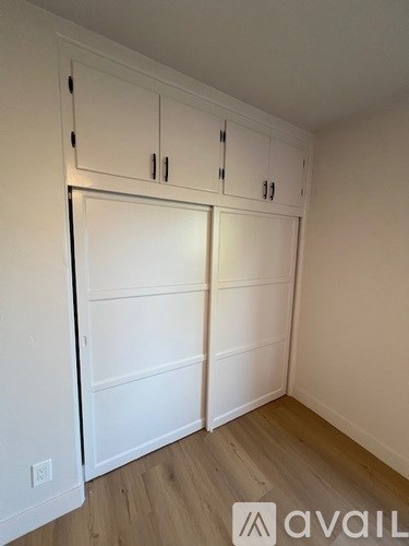 A room with white cabinets and a wooden floor.