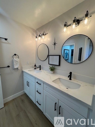 A bathroom with a white counter top and a round mirror above it.