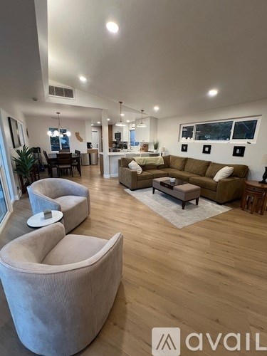 A living room with a couch, chairs and a rug.