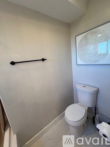 A white toilet in a small bathroom with a towel rack on the wall.