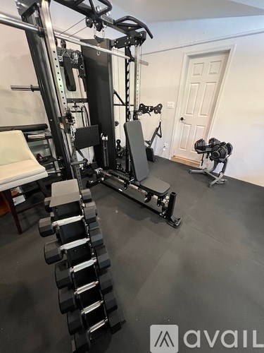 A home gym with a variety of equipment including a squat rack, bench, and weights.