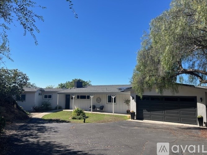 A house with a garage and a tree in front.