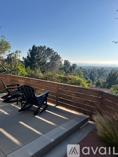 A patio with chairs and a view of the trees.