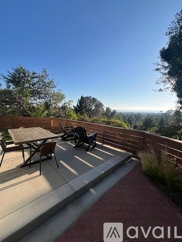 A patio with a table and chairs overlooking a scenic view.