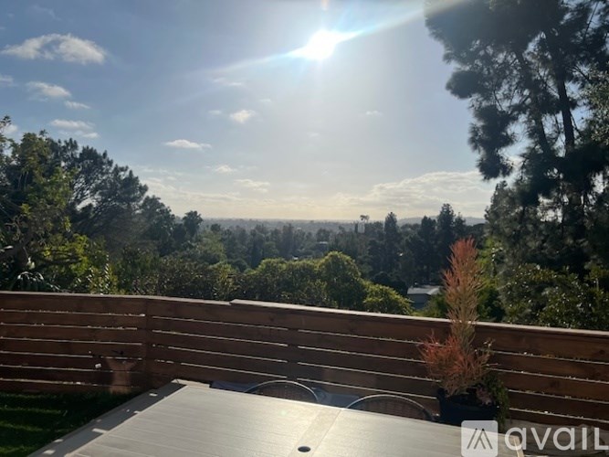 A wooden deck overlooks a lush green landscape under a clear blue sky.