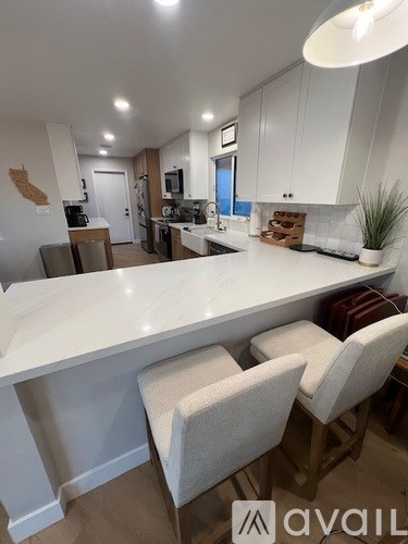 A kitchen with a white countertop and white chairs.