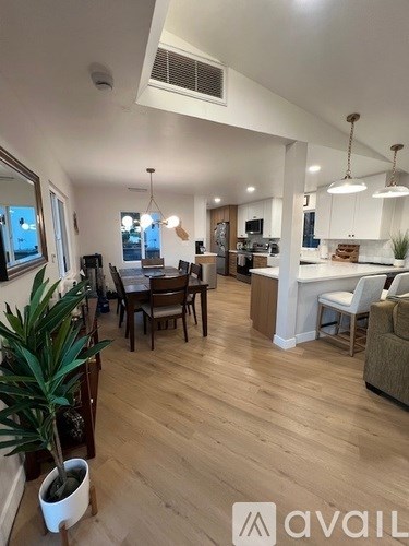 A well-lit open plan living and dining area with wooden floors and furniture.