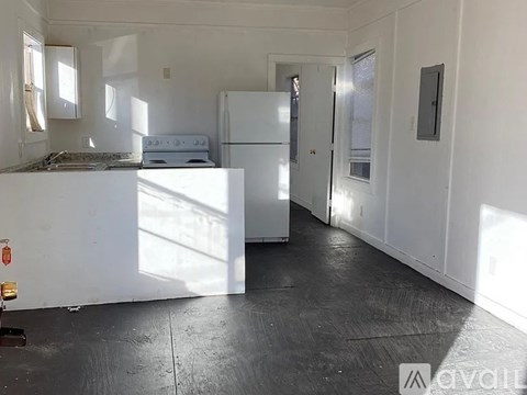 A kitchen with white appliances and cabinets is empty and ready for renovation.