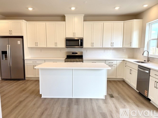 A kitchen with white cabinets and a white island.
