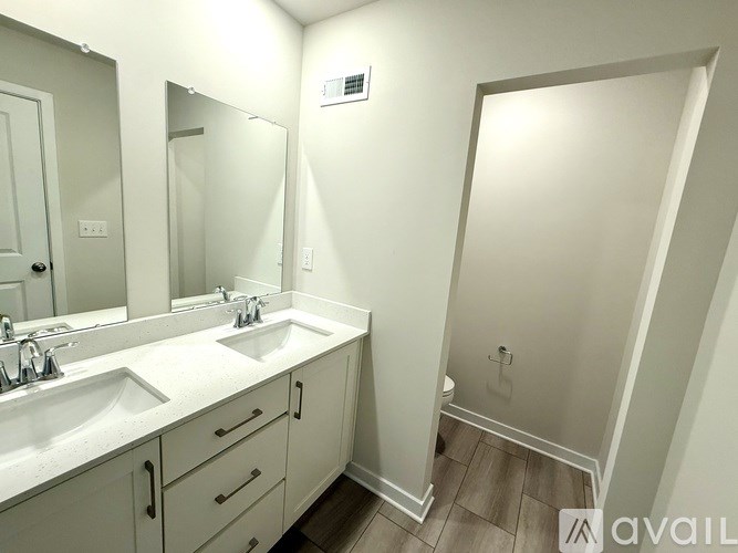 A bathroom with a sink, mirror, and a toilet in the background.