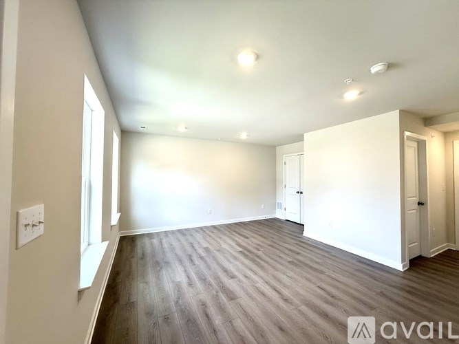 A spacious room with wooden flooring and white walls.