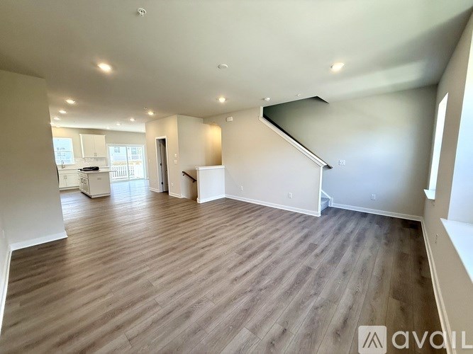 A spacious room with wooden flooring and white walls.