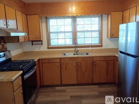 A kitchen with wooden cabinets and a stainless steel refrigerator.