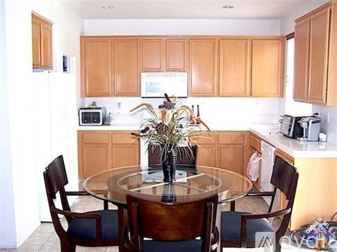 A kitchen with wooden cabinets and a glass table with chairs around it.