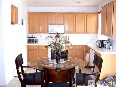 A kitchen with wooden cabinets and a glass table with chairs around it.