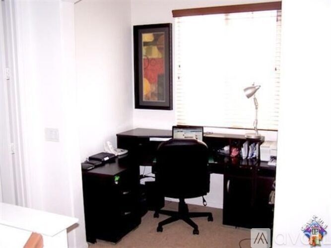 A black computer desk with a monitor, keyboard, and mouse on it.