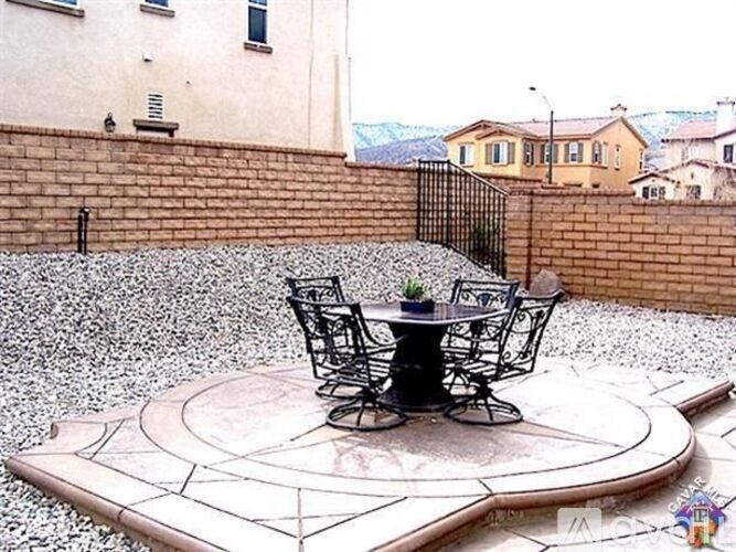 A patio with a table and chairs set on a stone floor.