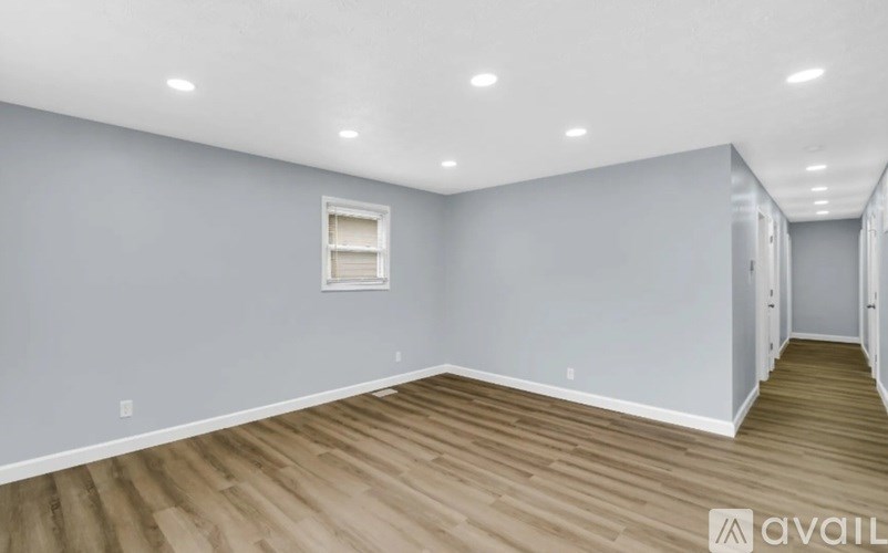 A room with wooden flooring and a window with blinds.