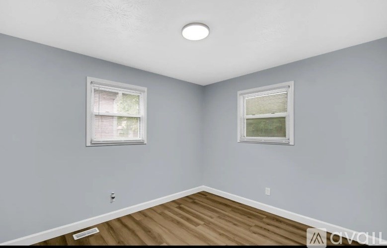 A room with two windows and wooden flooring.