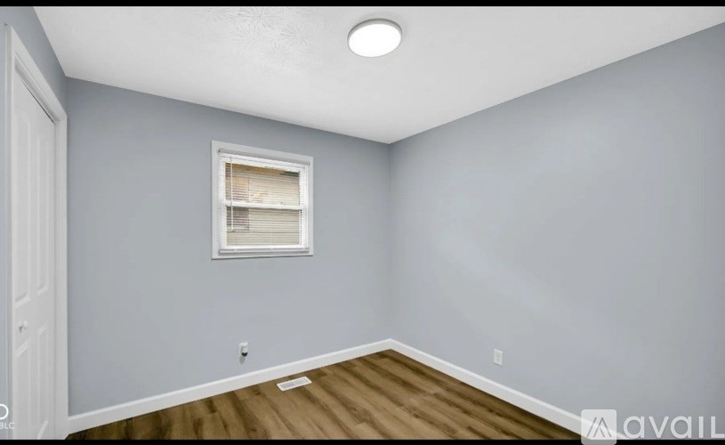 A room with a window and a wooden floor.