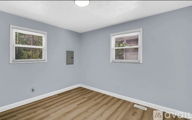 A room with two windows and wooden flooring.