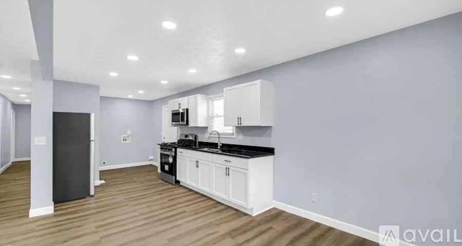 A modern kitchen with white cabinets and a black countertop.