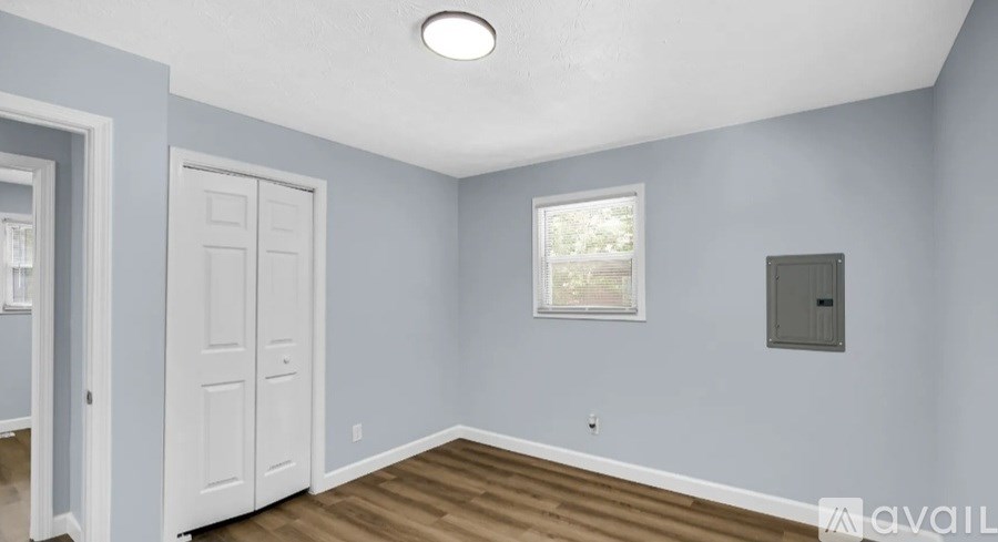 A room with a white door, a window, and a light on the ceiling.