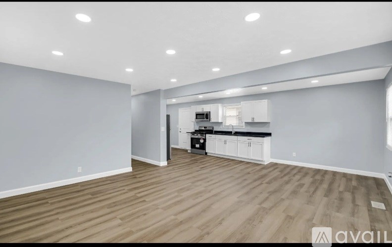A spacious living room with a kitchen in the background.
