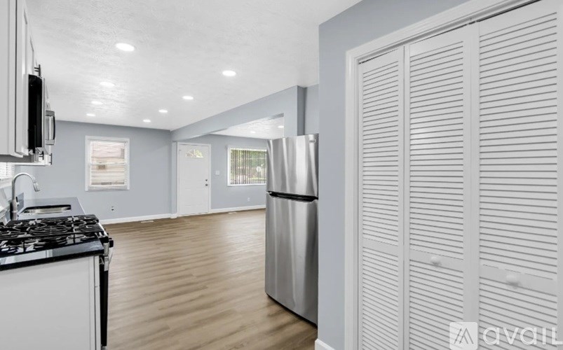 A modern kitchen with a stainless steel refrigerator and wooden flooring.