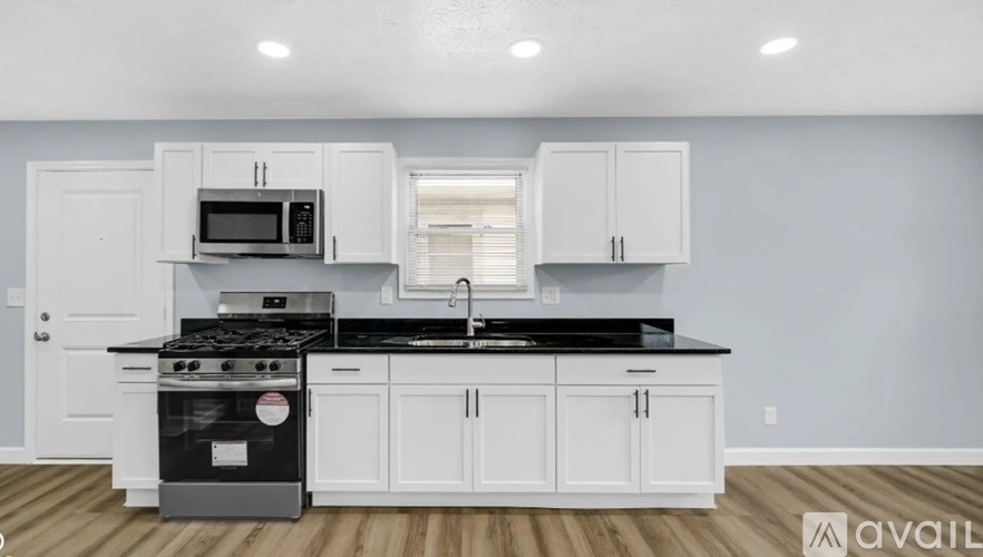A kitchen with white cabinets and a black countertop.