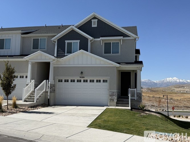 A modern house with a garage and a mountain in the background.