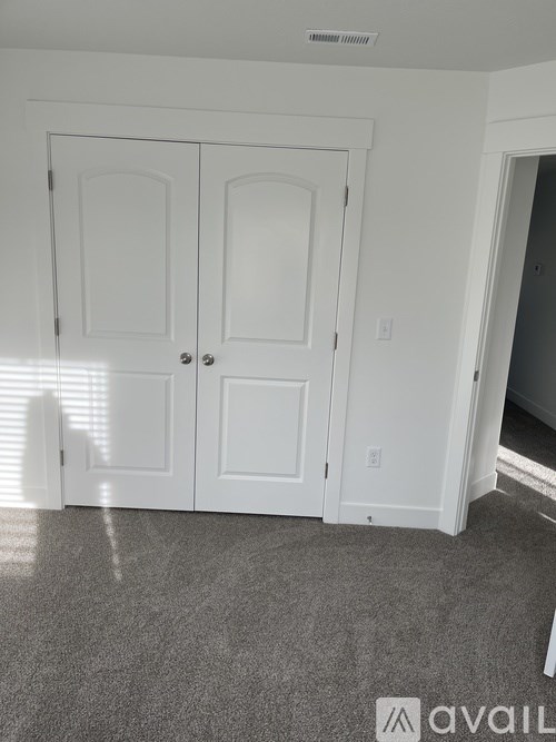 A room with white doors and a grey carpet.