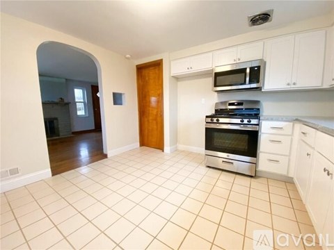 A kitchen with white cabinets and a tiled floor.