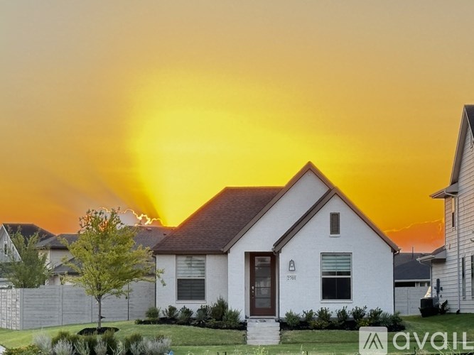 A house with a brown door is in the foreground with a sunset in the background.