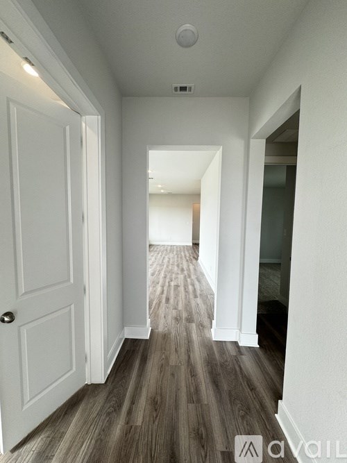 A hallway with a white door and wooden flooring.