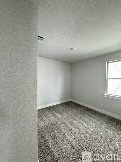 A room with a carpeted floor and a window with blinds.