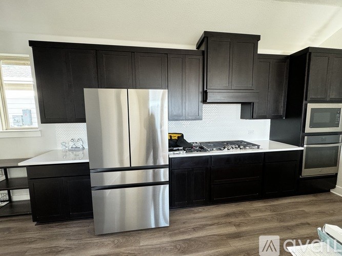 A modern kitchen with a stainless steel refrigerator and black cabinets.