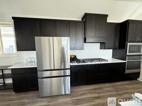 A modern kitchen with a stainless steel refrigerator and black cabinets.