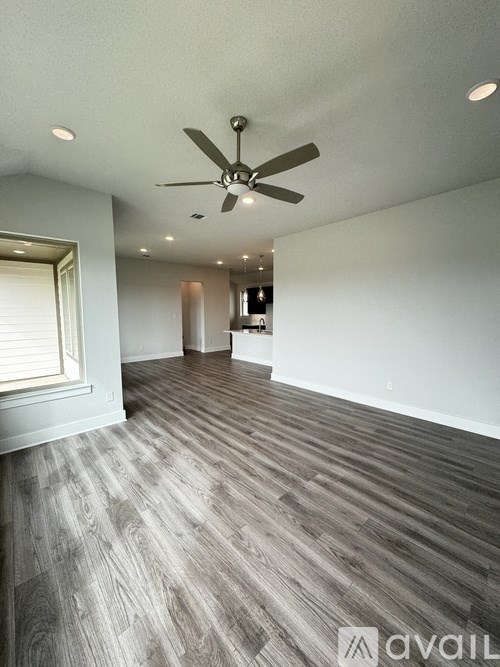 A room with a ceiling fan and wooden flooring.