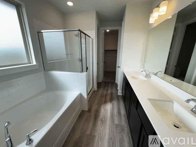 A bathroom with a white tub, sink, and wooden floors.