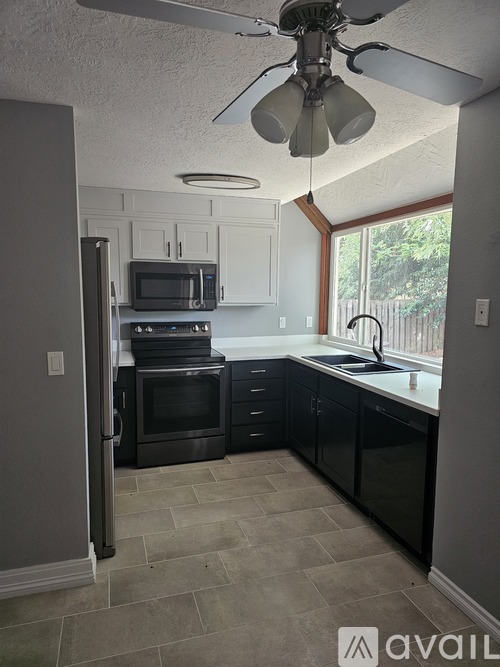 A kitchen with black appliances and a ceiling fan.
