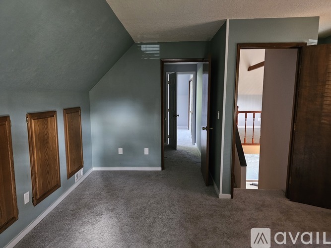 A room with grey carpet and wooden doors.