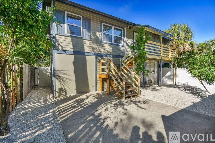A house with a wooden staircase leading to a garage.